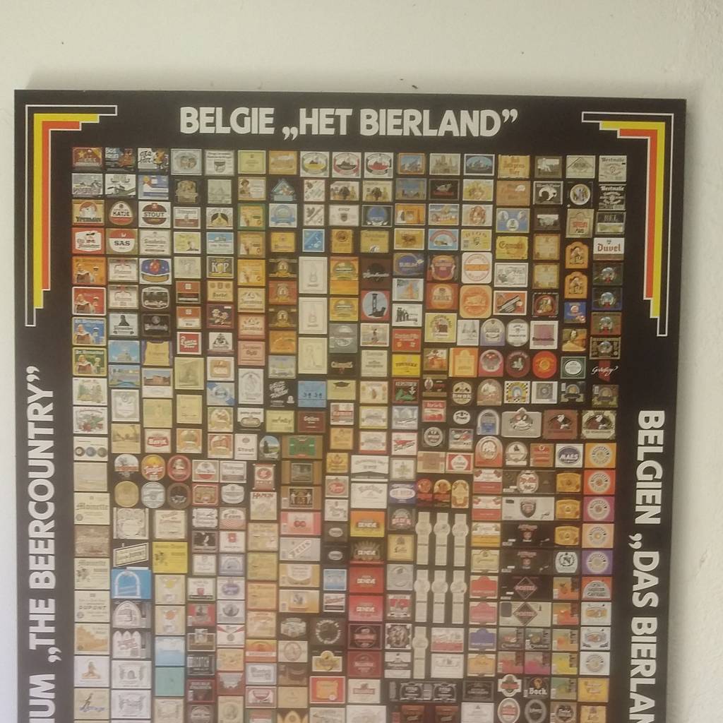 A poster of Belgian beer labels hanging on a wall at home.
