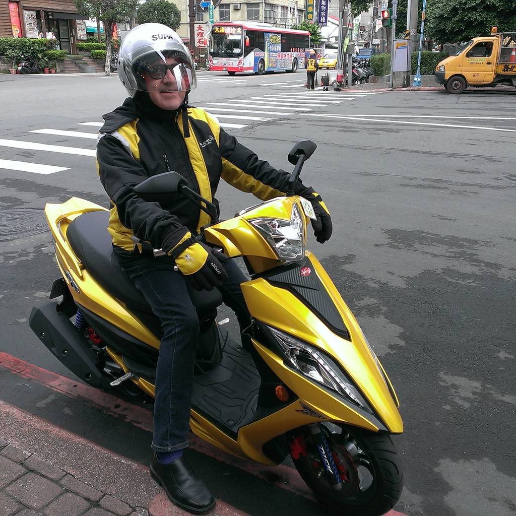 Jacques Botte on a yellow SYM scooter on a Taipei street, December 2015.