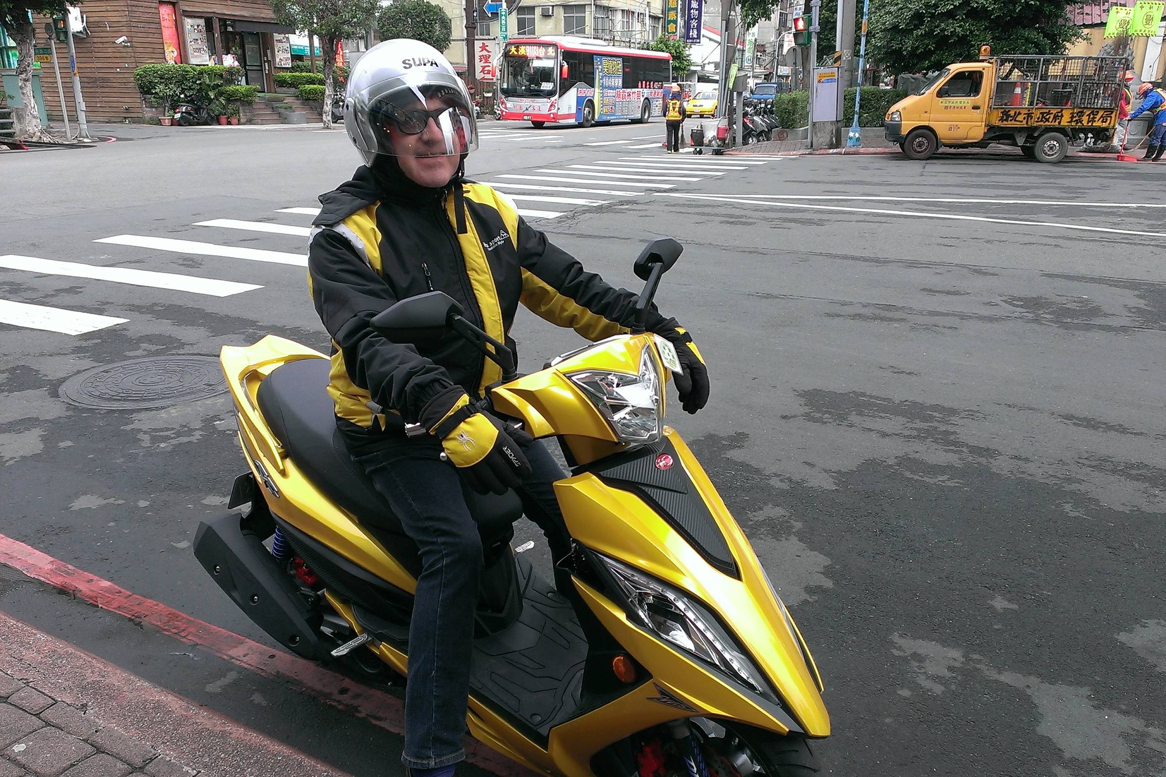 Jacques Botte on a yellow SYM scooter on a Taipei street, December 2015.